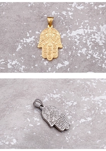 Detail of Hamsa hand pendants in gold and silver steel with swirl texture carving