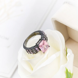Close-up of black plated S925 silver ring with pink princess cut stone in a white rose