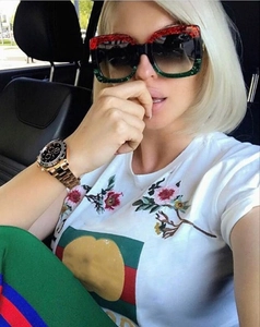 Detail of oversized square glitter sunglasses with green and red striped t-shirt