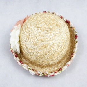 Detailed top view of natural straw sun hat with pink and white floral decoration