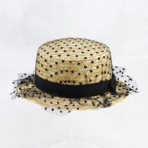Detail of wheat straw boater hat with black ribbon bow and polka dot mesh veil