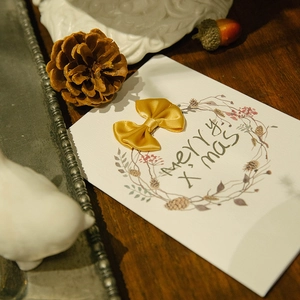 Christmas greeting card with yellow ribbon bow and floral wreath on vintage wood table