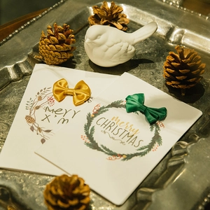 Elegant Christmas greeting cards with golden and green bows on vintage silver tray