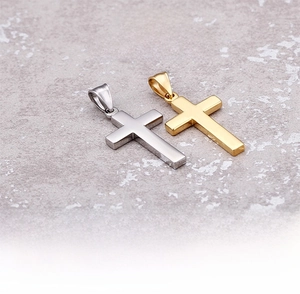 Polished titanium steel cross pendants in gold and silver finish on a textured stone surface