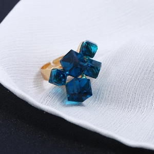 Macro di cristalli cubici blu su un anello aperto placcato oro su raso bianco lucido