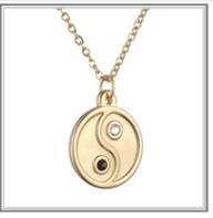 Detail of gold necklace featuring a Yin Yang pendant with black and white gemstones