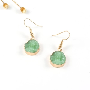 Detalle de pendientes de racimo de cristal de resina verde con marco dorado sobre fondo blanco