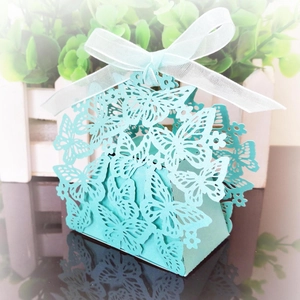 Close-up of laser-cut butterfly candy box in light teal with a white organza ribbon bow