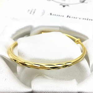 Elegant 18K gold plated bangle featuring a geometric faceted texture on white silk