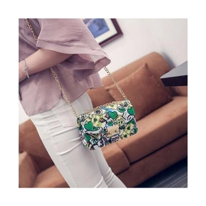 Green and white heart patterned crossbody bag with gold chain strap on model