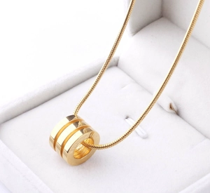 Close-up of golden cylinder pendant with 750 hallmark on snake chain in jewelry box