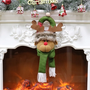 Plush Christmas reindeer door hanging ornament with knit details on a warm fireplace