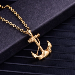 Detail of a golden anchor pendant with rope texture resting on a premium dark gift box