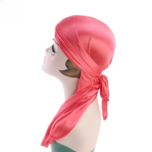 Detail of coral pink silky durag showing smooth satin texture and long tail ribbons