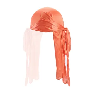 Detail of coral silky durag showing smooth satin texture and long tail ribbons