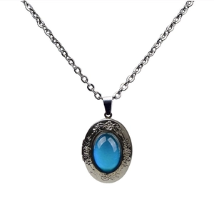 Detail of vintage silver locket with blue gemstone and floral engraving on an O-chain