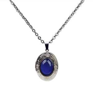 Macro detail of vintage silver oval pendant with blue gemstone and floral engraving