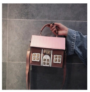 Detailed view of the house-shaped handbag featuring pink roof and metal turn-lock closure