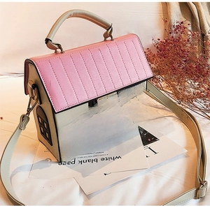 Close-up of creative house shaped handbag featuring pink roof and gold metal clasp
