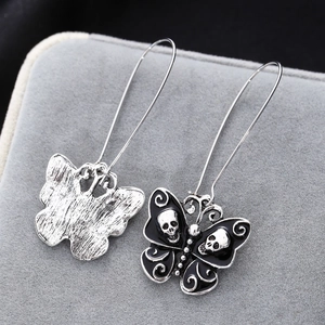 Macro view of gothic skull and butterfly earrings with black oil drop finish