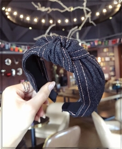 Detail of dark blue denim headband with stylish knot and pink contrast stitching