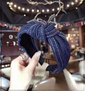 Close-up of denim headband featuring orange contrast stitching and knotted fabric detail