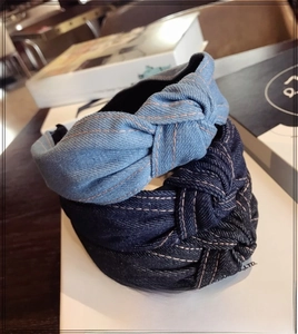 Close-up of knotted denim headbands in light blue, dark blue, and black with contrast stitching