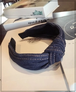 Detail of dark blue denim knotted headband with yellow contrast stitching on books