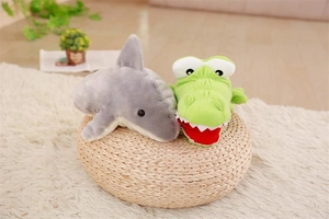 Detail of plush grey shark and green crocodile hand puppets on a cozy yellow cushion