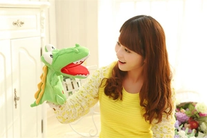 Detail of a green plush crocodile hand puppet with yellow scales for storytelling