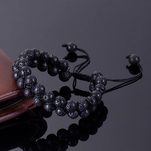 Macro detail of double-layered black lava rock stone beads on a woven adjustable bracelet