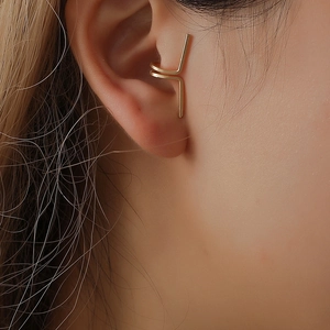 Detail of a minimalist gold double-layer geometric cuff earring on a model's ear