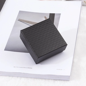 Black square jewelry gift box with diamond texture on a stylish magazine background