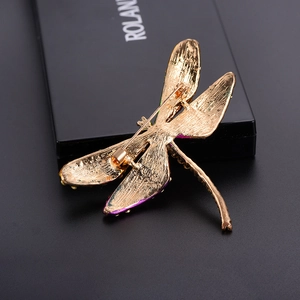 Detail view of gold alloy dragonfly brooch back with secure pin clasp on black background