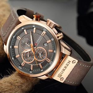 Detail of Curren chronograph watch featuring rose gold case and brown leather strap texture