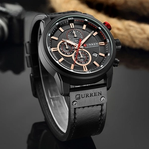 Detail view of black chronograph watch with rose gold indices and date window