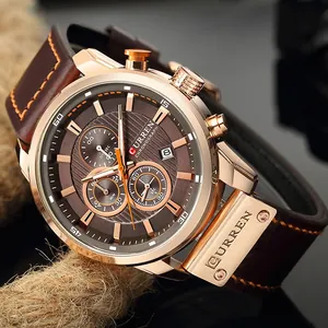 Macro shot of rose gold business watch crown and brown leather strap with orange stitching