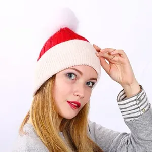 Detail of red and white ribbed knit beanie featuring a fluffy white faux fur pompom top