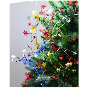 Close-up of colorful reflective star garlands on a Christmas tree branch