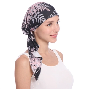 Detail of female printed headscarf with pink and grey fern leaf patterns on black fabric