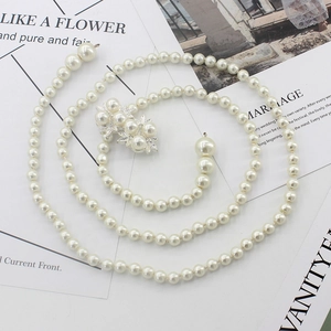 Ensemble élégant collier long multi-rangs en perles crème et broche posé sur un magazine
