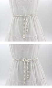 Détail de chaîne de taille en perles blanches avec boucles en strass sur robe en dentelle