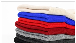 Close-up of folded winter beanies in multiple colors showing ribbed knit texture and variety