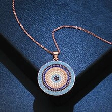 Detail of rose gold Evil Eye pendant with colorful zircon stones on a navy jewelry box
