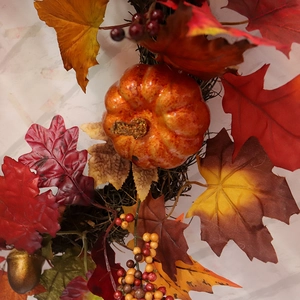 Autumn wreath with orange pumpkin, colorful maple leaves, and berries for Thanksgiving decor