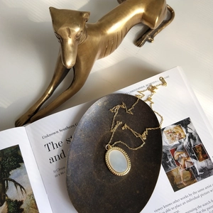 Close-up of vintage oval shell pendant necklace on an 18K gold plated chain