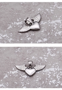 Detail view of silver heart pendant with textured angel wings on a stone surface