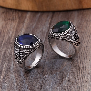 Bagues vintage pour hommes avec pierres bleues et vertes sur fond de bois naturel