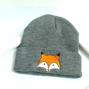 Gros plan sur la broderie de renard d'un bonnet en tricot gris pour enfant avec bord