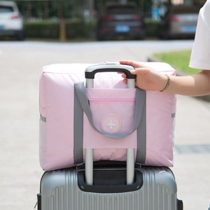 Pink foldable travel bag with trolley sleeve and waterproof fabric for easy luggage attachment